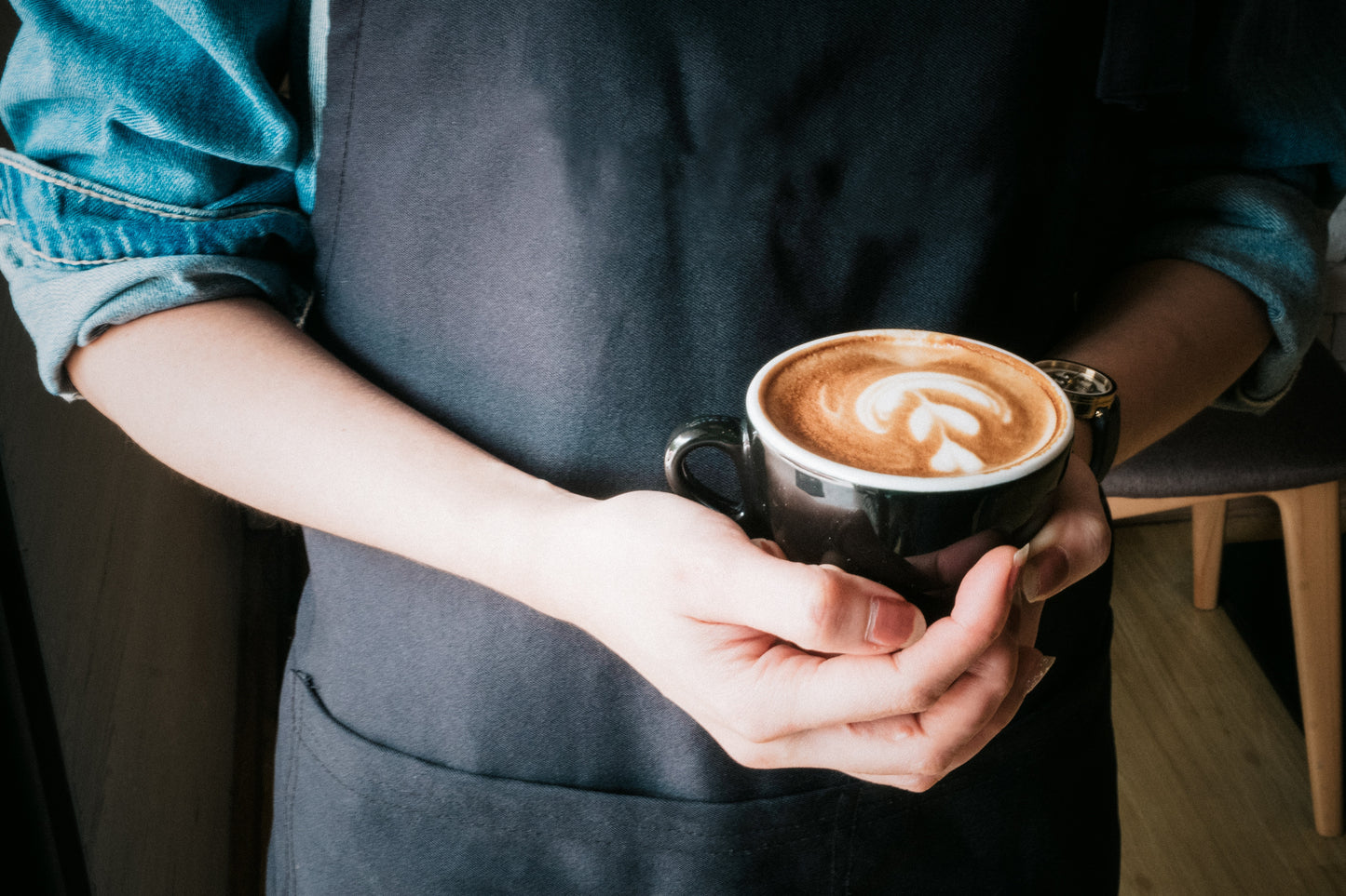Someone holding a cup of coffee with latte art on it.